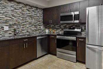 a kitchen with stainless steel appliances and wooden cabinets at The Pointe at St. Joseph Apartments, South Bend, IN